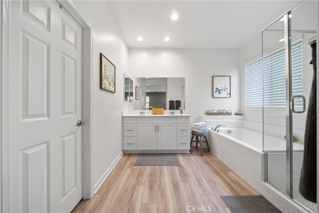 bathroom featuring a garden tub, a stall shower, wood finished floors, vanity, and recessed lighting