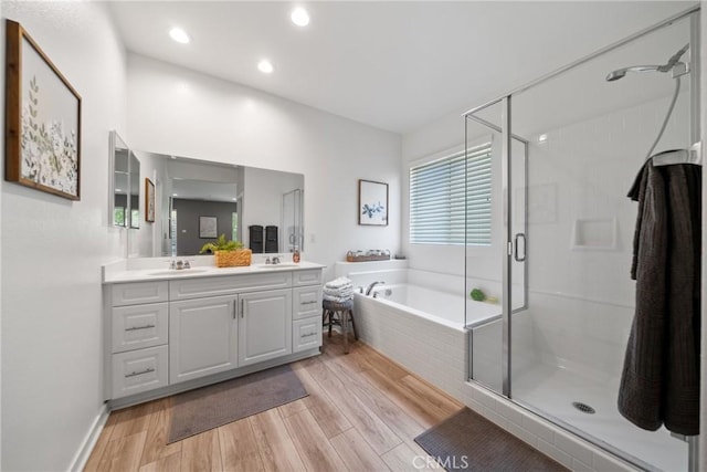 bathroom featuring a garden tub, a stall shower, wood finished floors, vanity, and recessed lighting