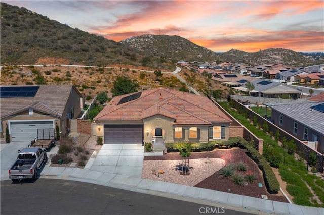 view of front facade featuring a tile roof, a garage, stucco siding, a mountain view, and concrete driveway