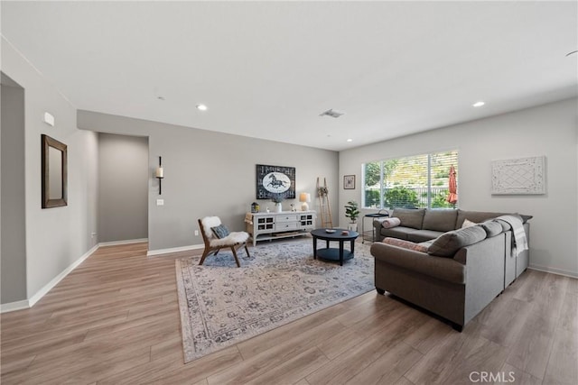living area with baseboards, visible vents, and light wood-style floors