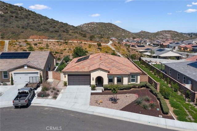 view of front of home featuring stucco siding, a tiled roof, an attached garage, a mountain view, and driveway