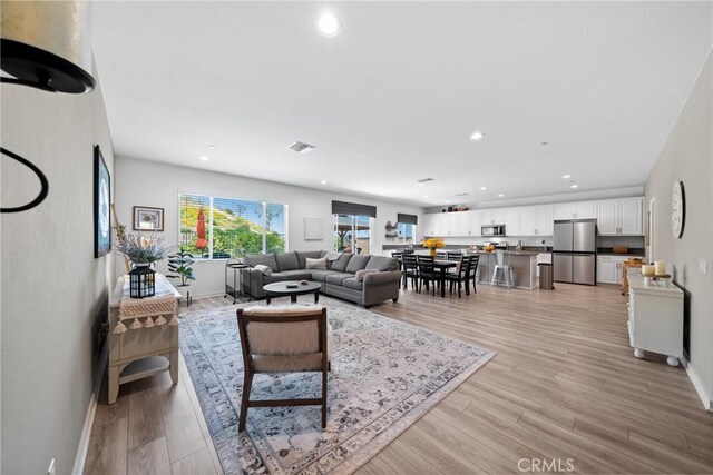 living area featuring baseboards, recessed lighting, light wood-style flooring, and visible vents