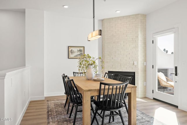 dining space with recessed lighting, baseboards, wood finished floors, and a fireplace