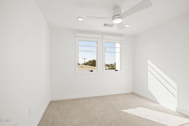 spare room with light carpet, a ceiling fan, visible vents, and baseboards