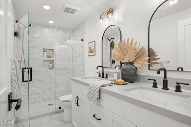 bathroom featuring visible vents, toilet, a stall shower, and a sink