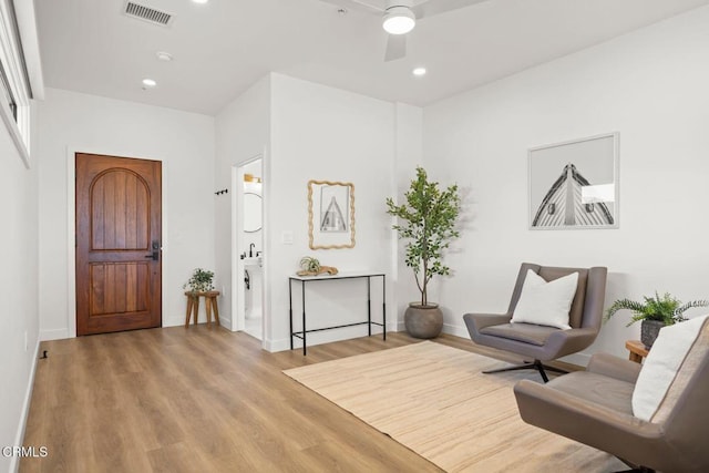 living area featuring baseboards, wood finished floors, visible vents, and a ceiling fan
