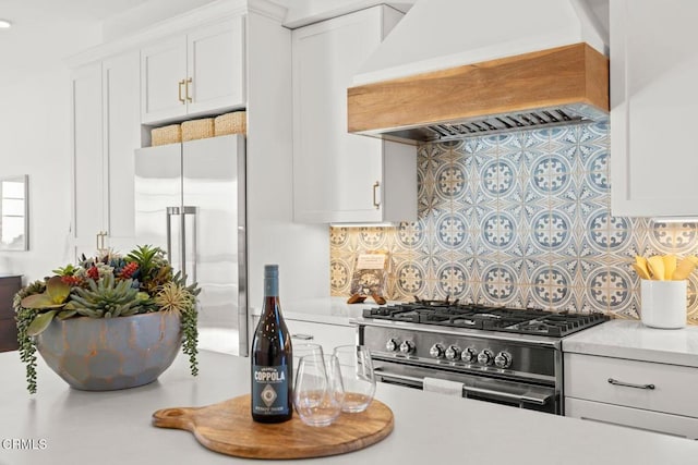 kitchen with white cabinets, light countertops, premium appliances, and custom range hood