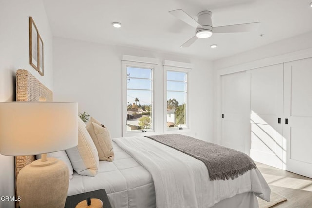 bedroom featuring light wood-type flooring, a ceiling fan, and a closet