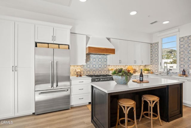 kitchen featuring a sink, visible vents, custom range hood, high end fridge, and light countertops