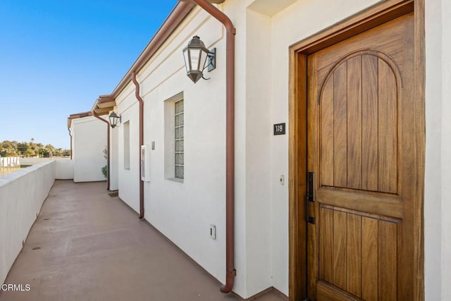 property entrance with stucco siding and a balcony
