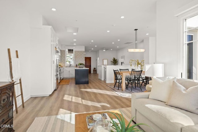 living area featuring recessed lighting, light wood-style flooring, and baseboards