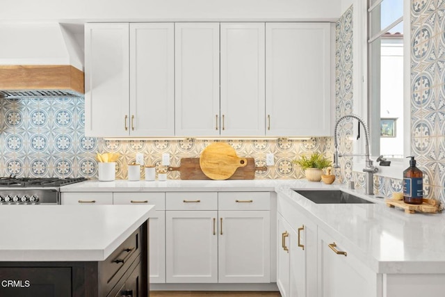 kitchen with light countertops, white cabinets, custom exhaust hood, and a sink