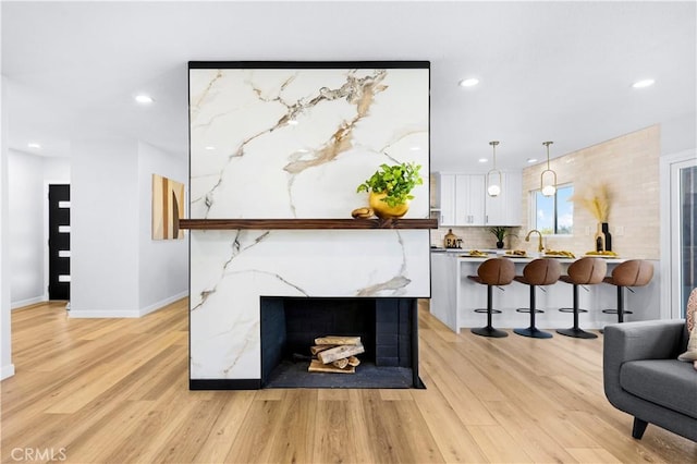 living room featuring light wood finished floors, baseboards, and recessed lighting