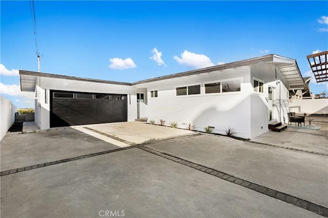 view of front of property featuring a garage, concrete driveway, fence, and stucco siding
