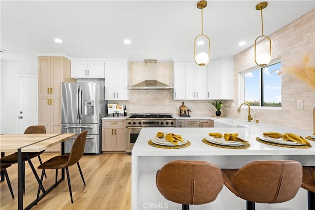 kitchen with tasteful backsplash, a sink, stainless steel appliances, light countertops, and wall chimney exhaust hood
