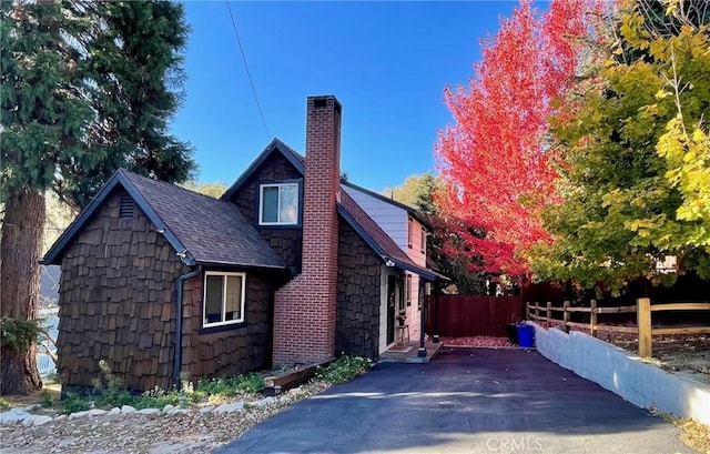29387 Lake View Dr, Cedar Glen, CA 92321 - view of property exterior with roof with shingles, fence, stone siding, and a chimney