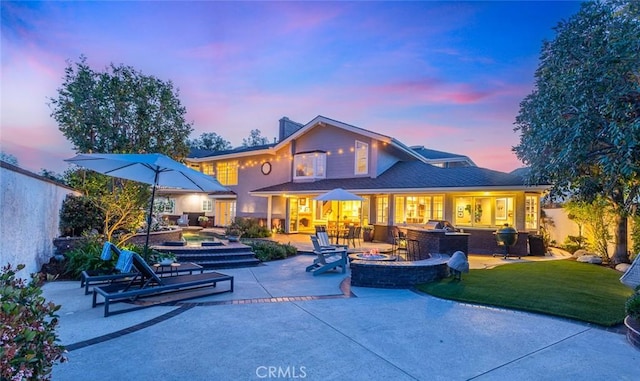 1232 Blue Gum Ln, Newport Beach, CA 92660 - back of house at dusk featuring a chimney, an outdoor fire pit, a lawn, and a patio area