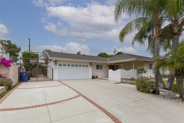 view of front of property featuring a garage, a gate, stucco siding, and driveway