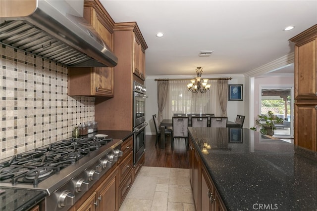 kitchen featuring visible vents, decorative backsplash, ventilation hood, a notable chandelier, and stainless steel appliances
