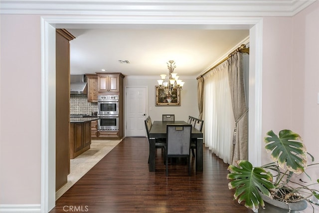 dining room featuring light wood-type flooring, ornamental molding, and a chandelier