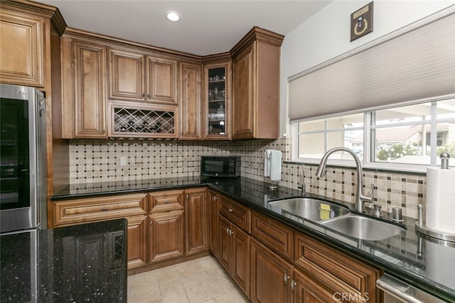 kitchen featuring a sink, dark stone countertops, backsplash, and stainless steel appliances