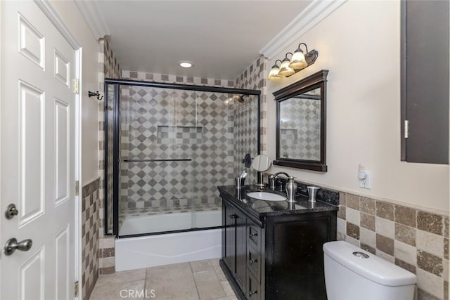 full bath featuring vanity, wainscoting, toilet, and tile walls