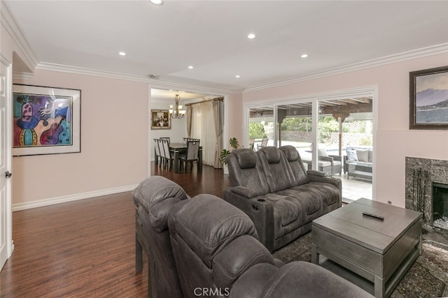 living room with crown molding, wood finished floors, a notable chandelier, and a premium fireplace