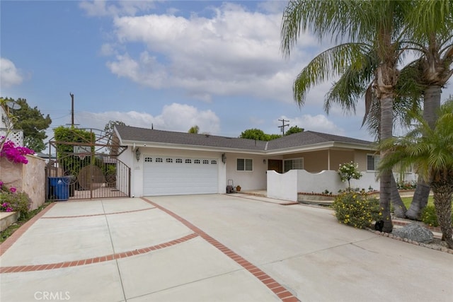 view of front of house featuring a gate, an attached garage, driveway, and stucco siding