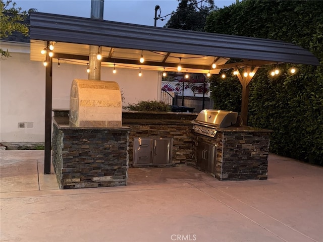 view of patio featuring fence, exterior kitchen, and area for grilling