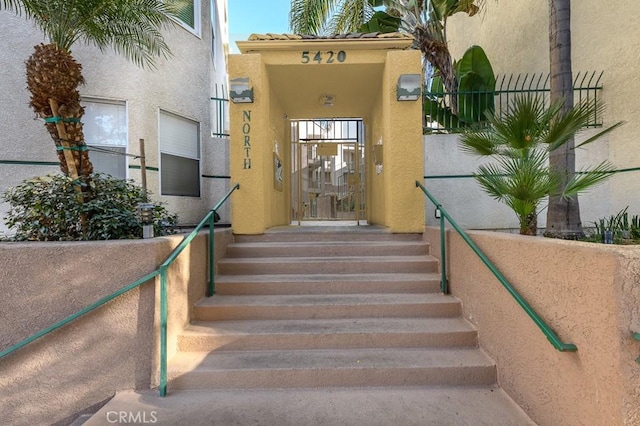 property entrance with stucco siding and fence