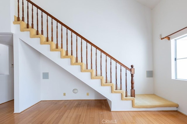 stairway featuring wood finished floors and a high ceiling