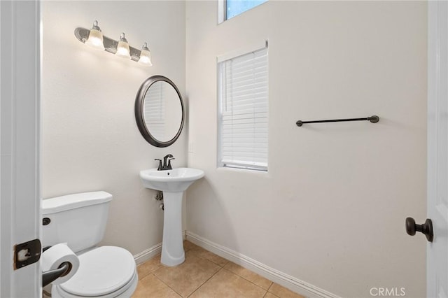 half bathroom with toilet, tile patterned floors, and baseboards