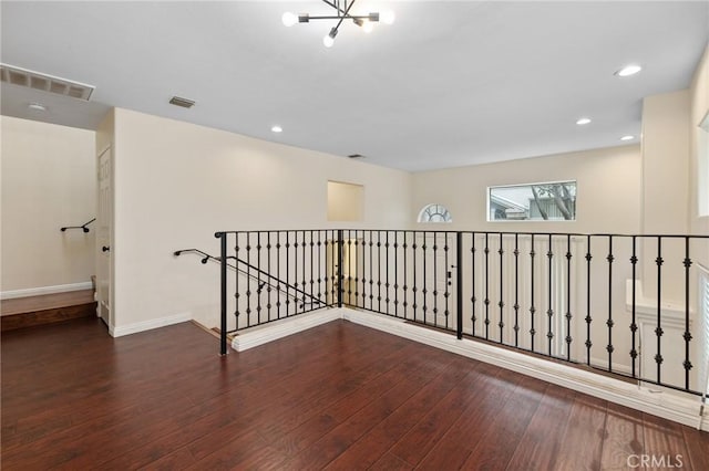 hallway featuring an inviting chandelier, wood finished floors, and visible vents