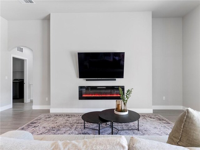 5211 Wingspan Ln, Bakersfield, CA 93306 - living area with wood finished floors, visible vents, a glass covered fireplace, and arched walkways