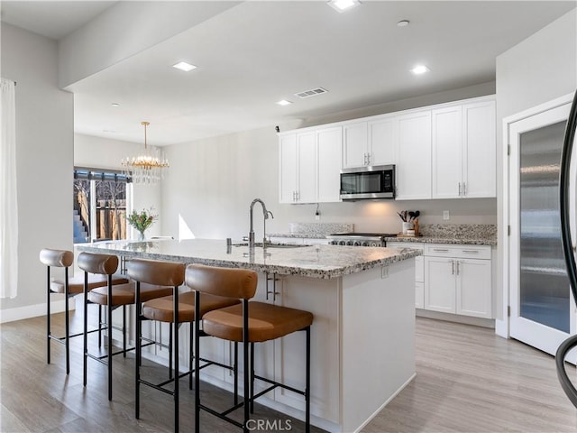 5211 Wingspan Ln, Bakersfield, CA 93306 - kitchen with stainless steel microwave, light wood-style floors, visible vents, and a sink