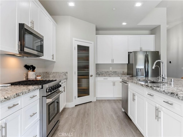 5211 Wingspan Ln, Bakersfield, CA 93306 - kitchen with white cabinets, a sink, light wood-style floors, stainless steel appliances, and light stone countertops