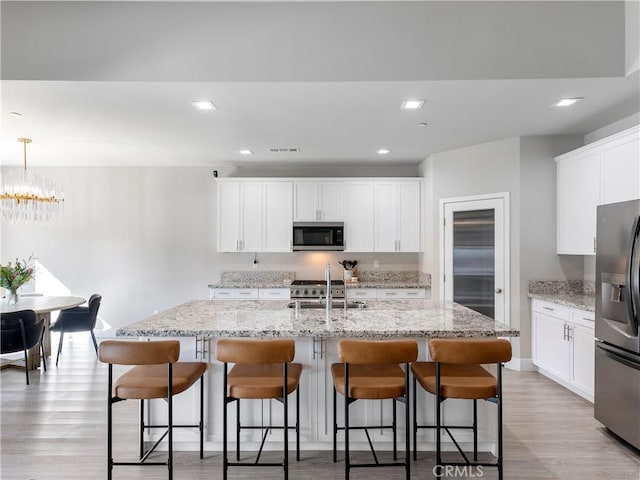 5211 Wingspan Ln, Bakersfield, CA 93306 - kitchen featuring stainless steel microwave, light wood-style floors, fridge with ice dispenser, and a sink