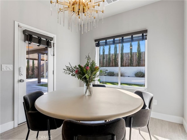 5211 Wingspan Ln, Bakersfield, CA 93306 - dining area featuring baseboards, a notable chandelier, light wood-style floors, and a wealth of natural light