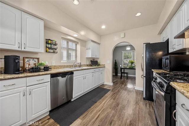 1229 Central Ave, Fullerton, CA 92831 - kitchen with appliances with stainless steel finishes, a sink, arched walkways, white cabinets, and light wood-style flooring