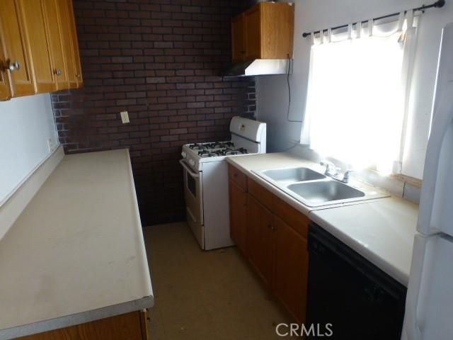 3465 Condor Rd Unit 29, Palms, CA 92277 - kitchen with brick wall, ventilation hood, white appliances, and a sink