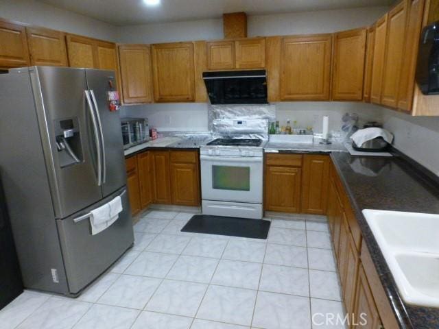 3465 Condor Rd Unit 29, Palms, CA 92277 - kitchen with brown cabinetry, stainless steel refrigerator with ice dispenser, a sink, and white gas range oven