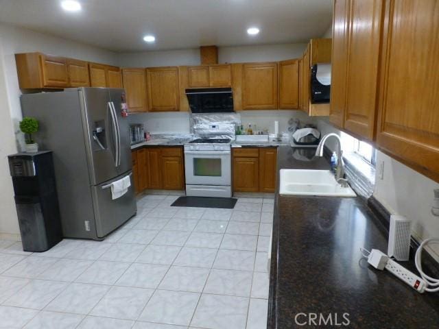 3465 Condor Rd Unit 29, Palms, CA 92277 - kitchen featuring a sink, brown cabinets, stainless steel fridge, white range with gas cooktop, and ventilation hood