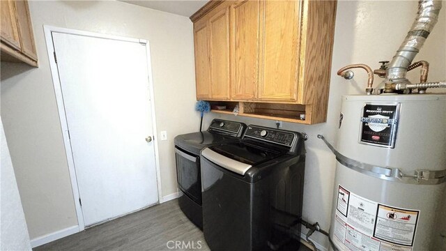 washroom featuring wood finished floors, water heater, cabinet space, washing machine and dryer, and baseboards