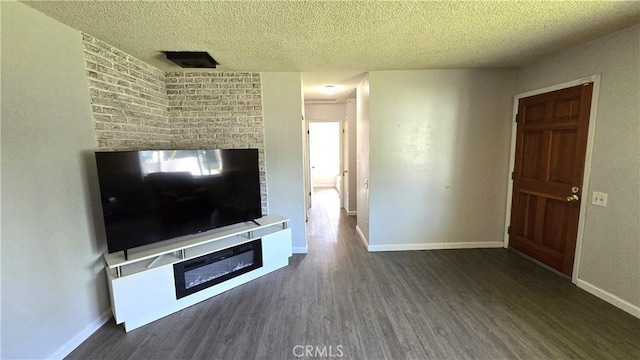 unfurnished living room featuring baseboards, a glass covered fireplace, wood finished floors, and a textured ceiling