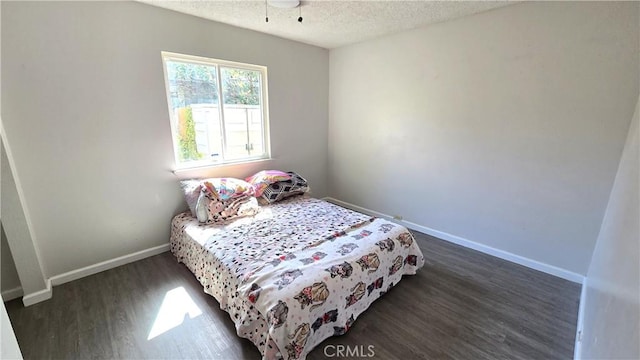 bedroom with baseboards, dark wood-style floors, and a textured ceiling