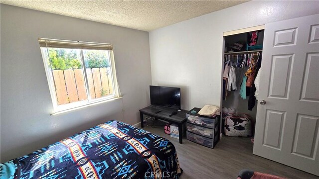 bedroom featuring a textured ceiling, wood finished floors, and a closet