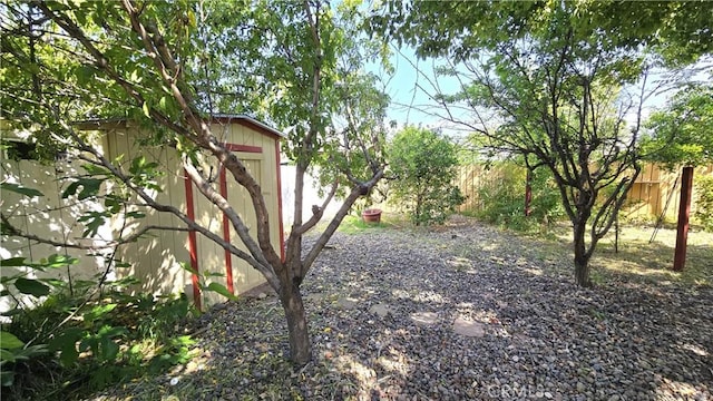 view of yard featuring a storage unit, an outbuilding, and fence