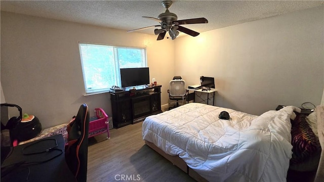 bedroom with ceiling fan, wood finished floors, and a textured ceiling