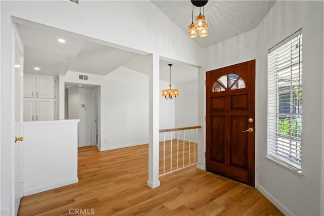 foyer with a chandelier, baseboards, light wood-style flooring, and lofted ceiling