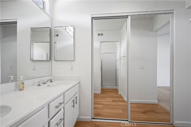 bathroom featuring wood finished floors, double vanity, and baseboards